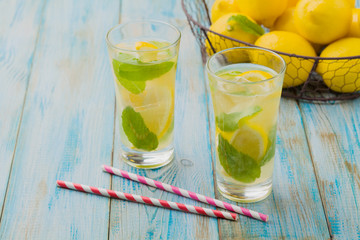 lemonade with mint on rocks served in a glass with a straw