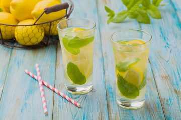 lemonade with mint on rocks served in a glass with a straw