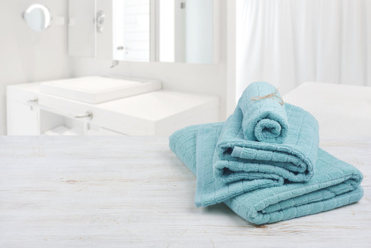 Turquoise spa towels on wooden surface over blurred bathroom background