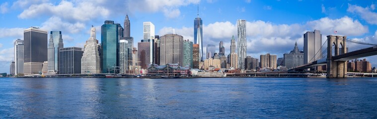 New York City Manhattan skyline panorama with Brooklyn Bridge and skyscrapers over Hudson River in the morning after sunrise.