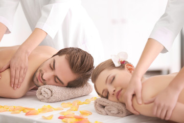 Obraz na płótnie Canvas Young happy couple having massage in spa salon