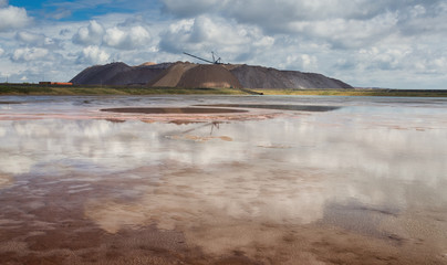 Extracting and mining potassium and magnesium salts.Blue Cloud Sky,Red Water,Large excavator machine ( dragline ) and Huge mountains of waste ore in the extraction of potassium. Belarus, Soligorsk.
