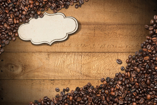 Roasted coffee beans on a wooden background with planks and a blank label