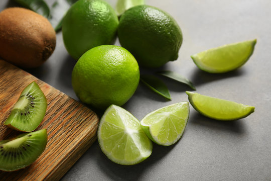 Wooden cutting board with fresh lime and kiwi fruits on grunge background