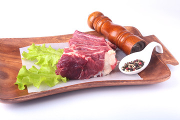 Raw beef edges, lettuce leaf, pepper grinder and spices on wooden desk isolated on white background from above and copy space. ready for cooking.