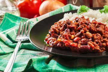 Hot chili con carne with ground beef, beans, tomatoes and corn served with rice
