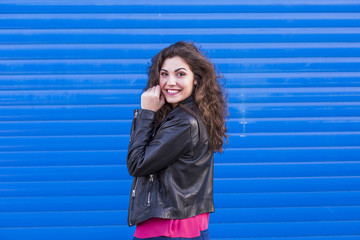 outdoors portrait of a beautiful Young woman over blue background. Happy. Colorful and lifestyle.