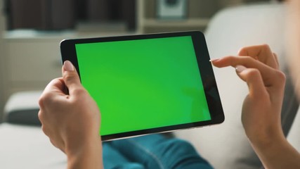 Woman hands using black tablet with green screen, lieng on sofa at home. View from the back. Chroma key. Close up. - Powered by Adobe