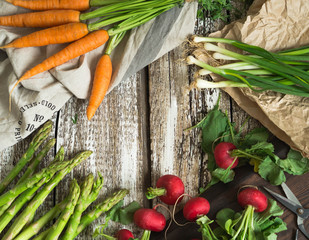 Spring vegetables - carrots, radishes, asparagus, green onions on an old wooden background. open space. Top view