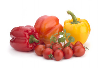 Cherry tomatoes, yellow sweet peppers and a basil branch on a white background
