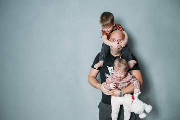 stressed young dad with two small children in his arms - obrazy, fototapety, plakaty