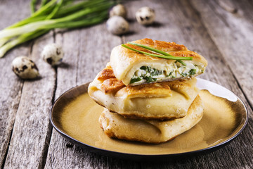 Patties with green onion, cottage cheese and egg filling on rustic wooden table. Fresh home baking. Selective focus  © trendyrowdy