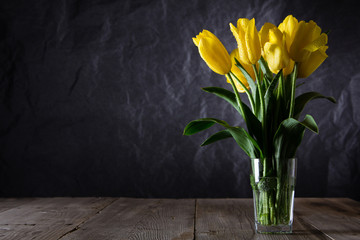 Bouquet of beautiful fresh yellow tulips in dew on dark background