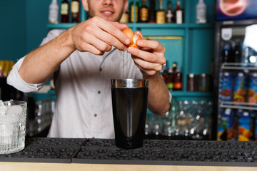 Barman's hands making cocktail with egg yolk