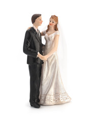 Fototapeta premium Figurines of a wedding cake on a white background, bride in a dress, bridegroom in a black tuxedo. Isolated
