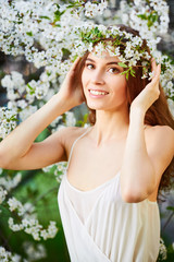 Young beautiful woman in white dress in circlet of flowers