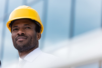 Close-up portrait of professional architect in hard hat looking away