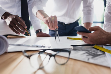 partial view of team of architects working on plan together in modern office