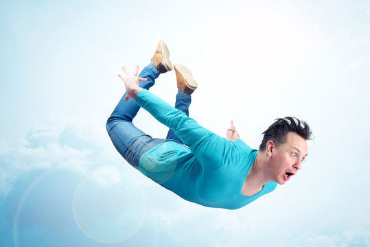 Crazy man in blue shirt and jeans is flying in the sky. Jumper concept