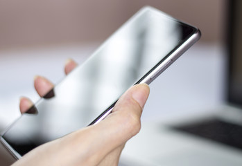 Hand holding mobile smartphone with blank screen.