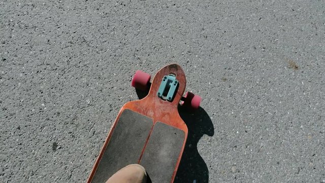 Man riding a longboard, a plan view on the move, close-up, first-person view. Lens, flare effect 20s 4k