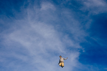 .Young attractive jumping excited with blue sky background. Lifestyle portrait.