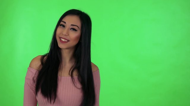 young attractive asian woman smiles - green screen studio