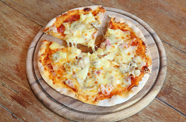 Delicious homemade pizza served on wood tray against wooden table
