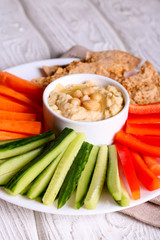 hummus served in a bowl with fresh vegetable sticks and whole grain crackers