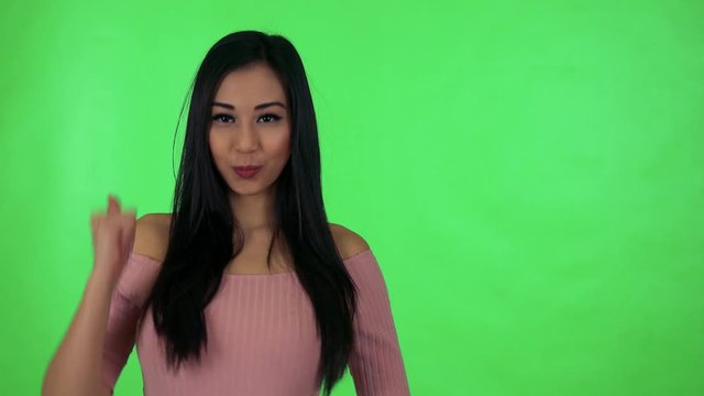 young attractive asian woman shows thumb on agreement - green screen studio