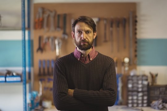 Portrait of serious owner standing at bicycle workshop