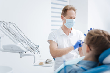 Focused friendly dentist preparing for procedure
