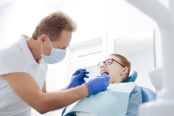 Obraz premium Sprytny, spostrzegawczy dentysta przeprowadzający badanie