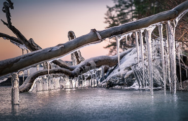 Scenic landscape with icicles and lake at the winter evening