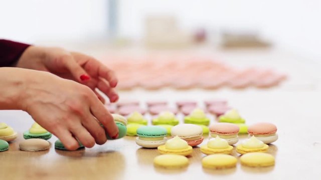 chef sandwiching macarons shells with cream