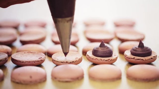 chef with injector squeezing filling to macarons