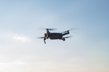 Black drone flying in blue sky 