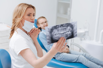 Thoughtful dedicated dentist diagnosing her patient - obrazy, fototapety, plakaty