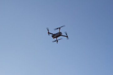 Black drone flying in blue sky 