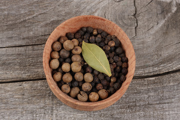black pepper. peppercorns in wooden bowl on wooden background with copy space. top view