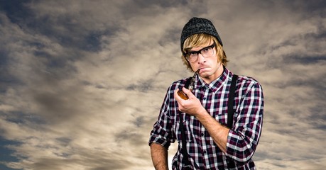 Confident hipster smoking pipe against sky