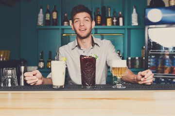 Young Barman offers cocktails in night club bar