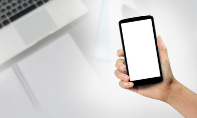 Hands holding smartphone with blank screen over the desk in office
