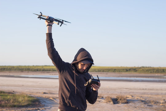 man hold in hand dron and remote controler, young man prepare quadrocopter to fly in desert 