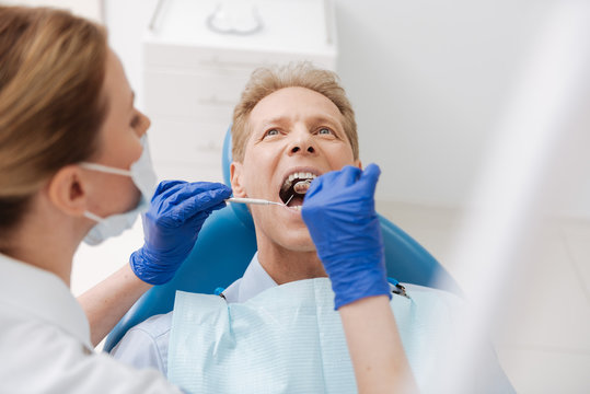Experienced dentist carefully examining patients cavity