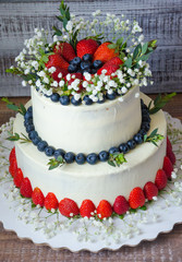 Obraz na płótnie Canvas two-tier cream cheese wedding cake with blueberries and strawberries