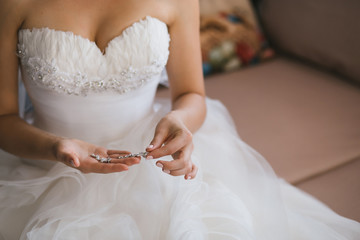 Obraz na płótnie Canvas Bride holding silver earrings. Tender hands with jewelry.