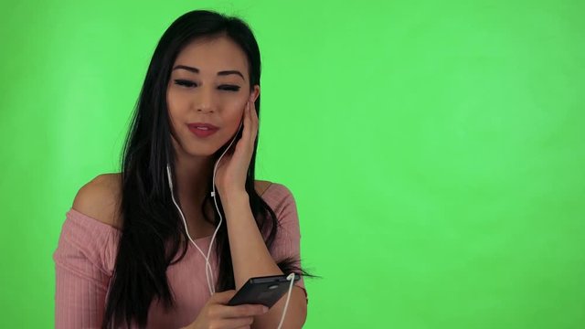 young attractive asian woman listens music with earphone (smartphone) and dances