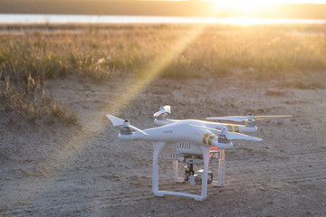 White drone with video camera stand on the sand 