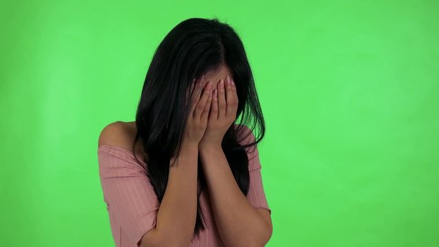 young attractive asian woman cries - green screen studio